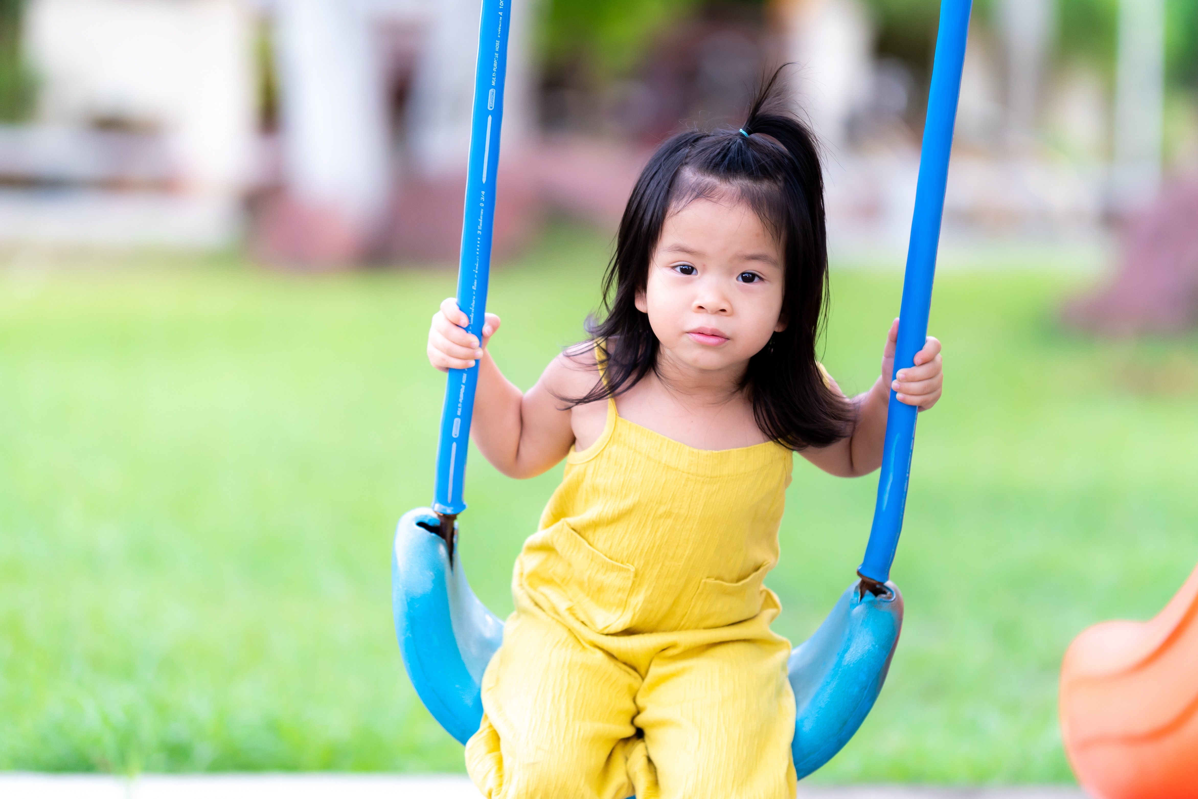 Active child having fun with swing chair at outdoor play area.