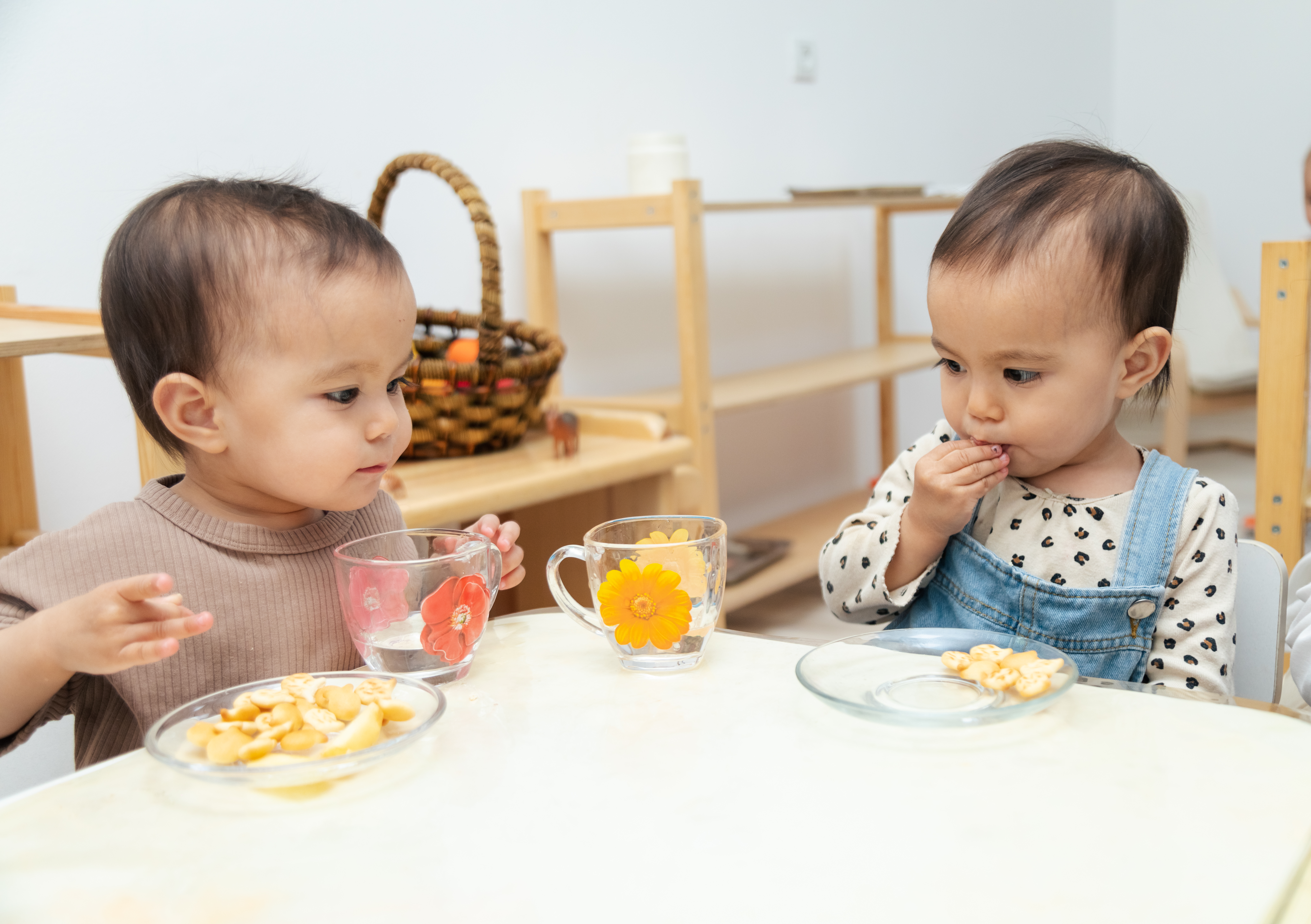 Toddlers eating snacks by table